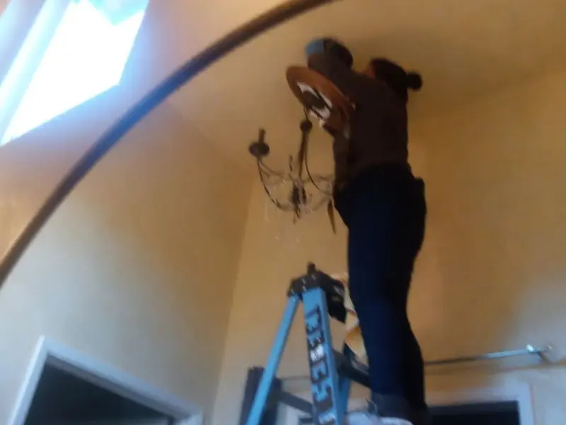 Electrician installing a chandelier in a Westville residence